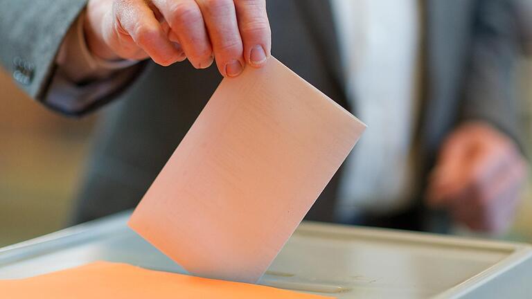 Ein Wähler wirft seinen Stimmzettel in eine Wahlurne (Symbolbild). In Sand können die Bürgerinnen und Bürger am Sonntag über einen neuen Bürgermeister abstimmen. Ein Wähler wirft seinen Stimmzettel in eine Wahlurne (Symbolbild). In Sand können die Bürgerinnen und Bürger am Sonntag über einen neuen Bürgermeister abstimmen.