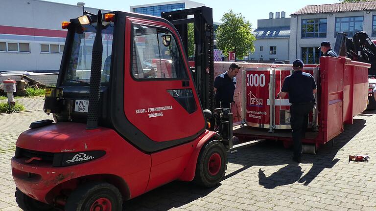 Feuerwehrleute der Staatlichen Feuerwehrschule Würzburg verladen einen Löschwasser-Außenlastbehälter.