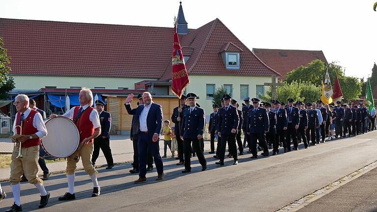 Mit einem Festzug zogen die Feuerwehrkameradinnen und Feuerwehrkameraden und ihre Gäste nach einem Gottesdienst in der Pfarrkirche zum Festgelände am Feuerwehrhaus. Die Musikkapelle Erbshausen-Sulzwiesen und Landrat Thomas Eberth führten den Zug an.