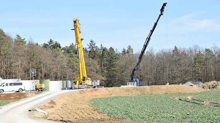 Kräne ziehen die Turmsegmente in die Höhe am Windpark Wargolshausen/Wülfershausen.