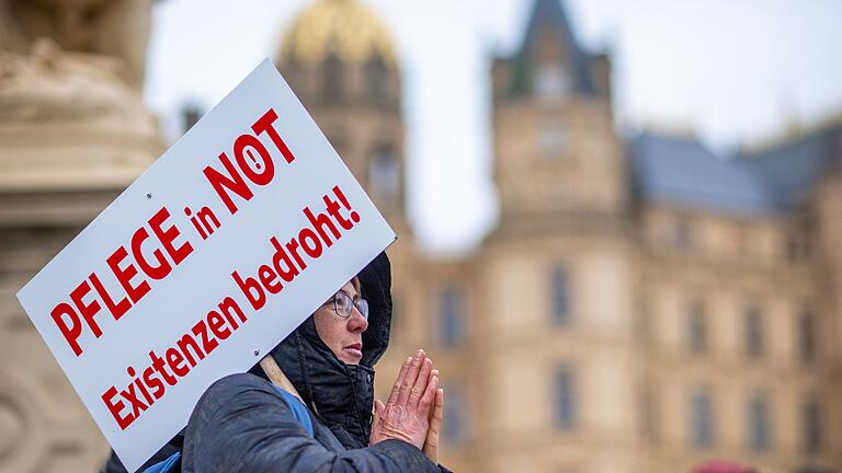 Protestaktion des Bündnisses 'Pflege in Not'.jpeg - Bei einer Protestaktion vor dem Schweriner Landtag hält eine Teilnehmerin ein Schild mit der Aufschrift «Pflege in Not - Existenzen bedroht!». Protestaktion des Bündnisses 'Pflege in Not'.jpeg - Bei einer Protestaktion vor dem Schweriner Landtag hält eine Teilnehmerin ein Schild mit der Aufschrift «Pflege in Not - Existenzen bedroht!».