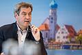 Markus Söder (CSU), Ministerpräsident von Bayern, sitzt vor Beginn einer Online-Sitzung des bayerischen Kabinetts an seinen Platz vor einer Fotowand. (Archivbild)