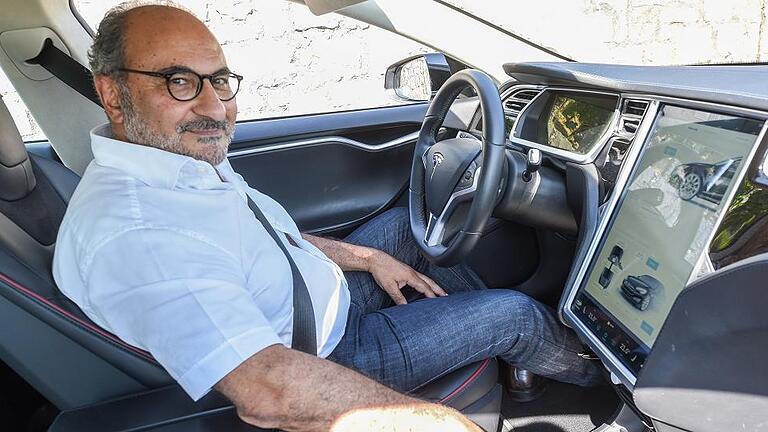 Frühstückt jetzt im Auto, während es lädt: Farroch Radjeh, der 80 000 Kilometer im Jahr mit dem Tesla unterwegs ist.