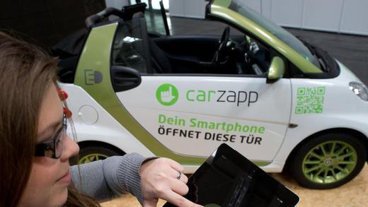 CeBIT 2013       -  Eine Mitarbeiterin der Firma carzapp demonstriert, wie man mit einem Tablet oder Smartphone die Tür eines 'geteilten' Autos öffnen kann. Foto: Jochen Lübke