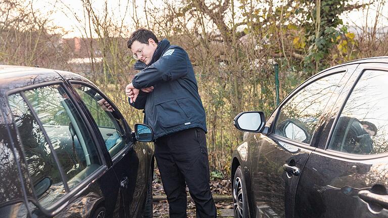 Marcel Ködderitzsch prüft auf einem Parkplatz in Marktheidenfeld mit einem Blick auf seine Armbanduhr, ob die Parkscheibe die korrekte Ankunftszeit anzeigt.