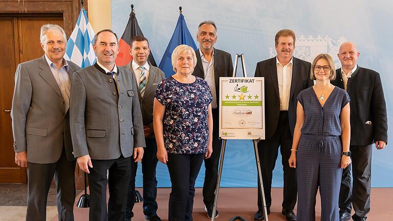 Wirtschaftsminister Hubert Aiwanger übergab die Auszeichnung an das Team vom Dorfladen Wiesenfeld mit Peter Knöll (Zweiter von rechts), Raimund Eirich (links), Franz Breitenbach (Dritter von rechts), Kerstin Ammerbach (vorne rechts) und Marion Dittmaier, zusammen mit Wolfgang Gröll (rechts) vom Bundesverband der Bürger und Dorfladen.