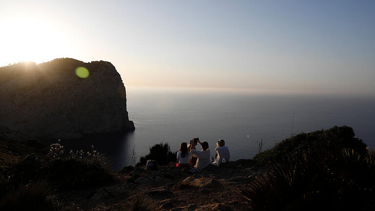 287574128.jpg       -  Wer nach einer langen Wanderung eine Pause machen möchte, findet auf Mallorca viele geeignete Plätze. Eine besonders beliebte Aussicht: der Sonnenuntergang an der Küste.