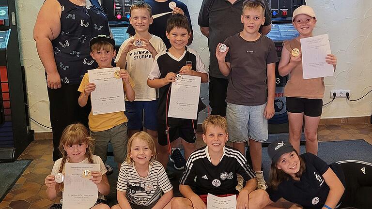 Gruppenbild der zehn teilnehmenden Kinder mit dem Jugendtrainer des Unterfränkischen Dart Verbandes Georg Geuppert und der Vereinsvorsitzenden des DC Hau Wech … e.V. Sabrina Elbert.