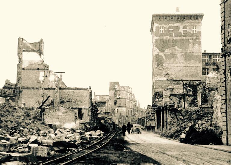 Die Augustinerstraße mit dem Ämterhochhaus. Dieses hatte den 16. März überstanden, weil es aus Beton errichtet worden war. Die Schienen links gehören zu einer Schmalspurbahn, mit der Trümmerschutt zum Main gefahren und auf Transportschiffe geladen wurde. Die Augustinerstraße mit dem Ämterhochhaus. Dieses hatte den 16. März überstanden, weil es aus Beton errichtet worden war. Die Schienen links gehören zu einer Schmalspurbahn, mit der Trümmerschutt zum Main gefahren und auf Transportschiffe geladen wurde.