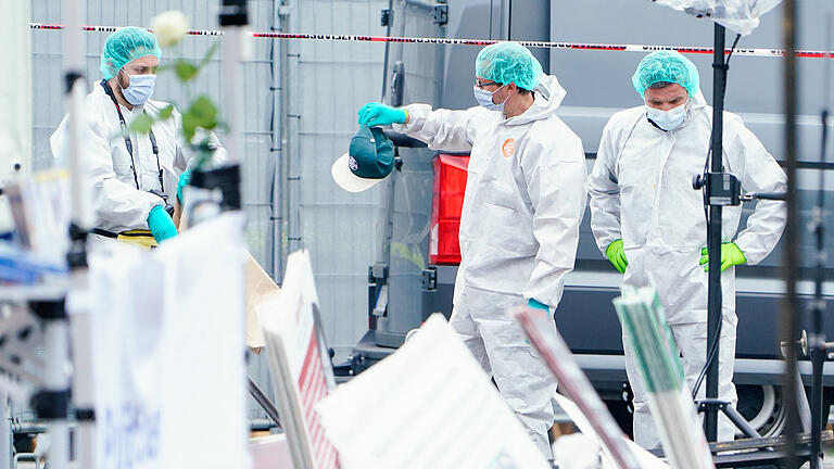 Mannheim - Messerangriff auf Marktplatz.jpeg       -  Mitarbeiter der Spurensicherung halten an einem Stand auf dem Marktplatz eine Kappe in den Händen. Bei einem Einsatz auf dem Mannheimer Marktplatz hat die Polizei einen Angreifer niedergeschossen.