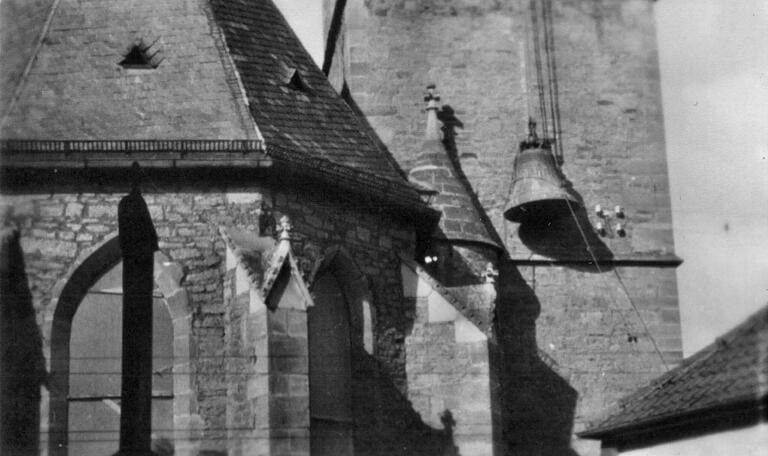 Ein betrüblicher Moment: Die von Valentin Schmitt gestiftete große 'Dreifaltigkeitsglocke' wird 1942 vom Nordturm des Steigerwalddoms herabgelassen. Auf dieser historischen Fotografie ist auch zu erkennen, dass damals die hohen Fenster der Apsis der Kirche (links) vermutlich aus Angst vor Kriegsschäden bereits mit Holzbrettern verschalt waren.