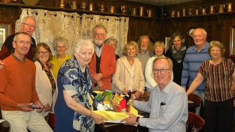 Im Vordergrund zu sehen Ann Roberts, Vorsitzende der Twinning Organisation beim Empfang vom Gastgeschenk in Form von fränkischen Leckereien, übergeben durch Burkard Bähr, Vorsitzender Städtepartnerschaftsverein Ochsenfurt.