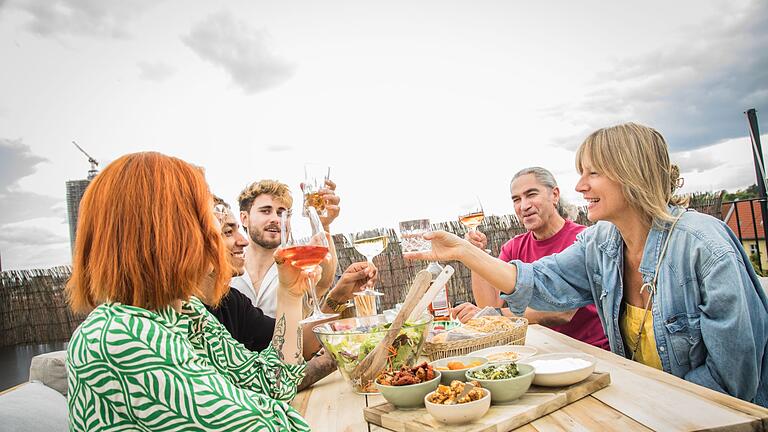 Ein Gruppe von Leuten sitzt auf einer Dachterrasse       -  Ein Festmahl: Nicht nur wir Menschen mögen Süßes und Gegrilltes - auch Wespen lieben es.