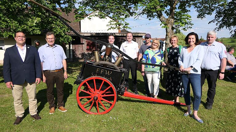 Mit der historischen Handpumpe wurde einst gelöscht. Über das 150-jährige Bestehen der Feuerwehr Schönbach freuen sich (von links): Bürgermeister Martin Horn, Altbürgermeister Walter Ziegler, Christopher Markert (Feuerwehr Schönbach), Kreisbrandinspektor Stephan Biertempfel, Martin Eltschka und Ingrid Markert (Obst- und Gartenbauverein), stellvertretende Landrätin Birgit Bayer, Bundestagsabgeordnete Dorothee Bär und stellvertretender Kommandant Sascha Schöpplein.