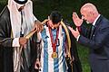 Der Emir von Katar, Scheich Tamim bin Hamad Al Thani (links), legt Argentiniens Lionel Messi vor Übergabe des WM-Pokals vor Fifa-Präsident Gianni Infantino (rechts) ein Bischt, ein traditionelles arabische Kleidungsstück an.