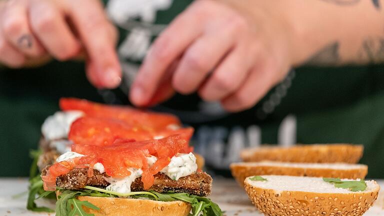 Eine Köchin belegt einen Burger mit veganem Fischersatz       -  Vegetarischer Lachs lässt sich einfach zu Hause zubereiten und ist ideal zum Brunch.