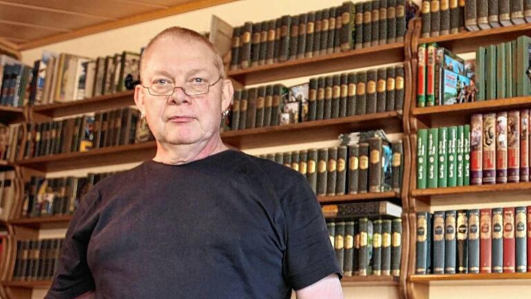 Karl May als Hobby: Peter Hartmann vor dem Regal mit 350 Bänden und einer frühen Ausgabe von Winnetou in den Händen.