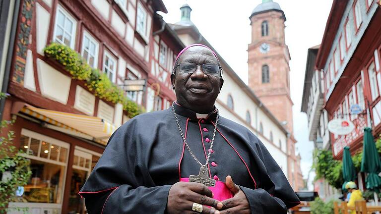 Bischof Francis Aquirinus Kibira mit der Miltenberger Pfarrkirche im Hintergrund.