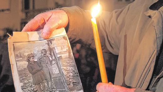 Erinnerung an Kriegsverbrechen: Panagiotis Sfoudouris, ein Überlebender des Massakers von Distomon, zeigt einen Zeitungsausschnitt von 1948. Auf dem Bild sind er und seine Schwester Maria am Grab der Eltern und des Bruders zu sehen.