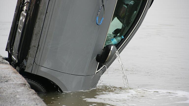 Langsam, Stück für Stück, hebt der Kran ein Auto am Kitzinger Mainkai aus dem Wasser.