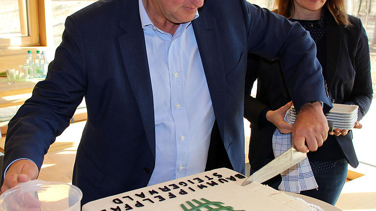 Der Vorstandsvorsitzende der Bayerischen Staatsforsten, Martin Neumeyer, beim Anschneiden der Torte zum einjährigen Bestehen des Baumwipfelpfades Steigerwald im März 2017 mit der damaligen Leiterin Miriam Langenbucher.