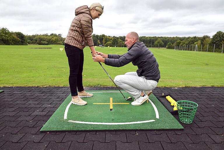 Golftrainer Colin Monk zeigt Isabel Rott die richtige Haltung des Golfschlägers.