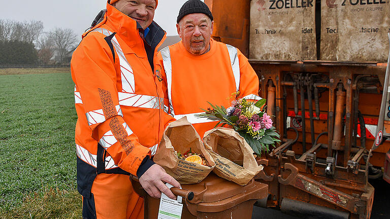 Die Müllwerker Hilmar Reder (links) und Lothar Ress zeigen hier, was in die Biotonne gehört, nämlich ausschließlich organische Reststoffe wie Küchen- und Gartenabfälle – am besten praktisch in einer Papiertüte gesammelt. Wo Fremdstoffe wie Plastik bei der Leerung gefunden werden, informiert künftig ein Anhänger mit wichtigen Informationen und Tipps rund um das Thema 'Kein Plastik in die Biotonne'. Die Müllwerker Hilmar Reder (links) und Lothar Ress zeigen hier, was in die Biotonne gehört, nämlich ausschließlich organische Reststoffe wie Küchen- und Gartenabfälle – am besten praktisch in einer Papiertüte gesammelt. Wo Fremdstoffe wie Plastik bei der Leerung gefunden werden, informiert künftig ein Anhänger mit wichtigen Informationen und Tipps rund um das Thema 'Kein Plastik in die Biotonne'. 