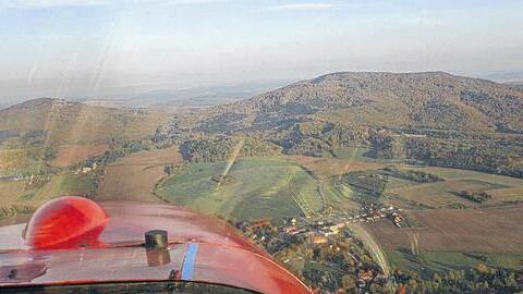 Südthüringen aus der Luft: Voraus sind die Gleichberge zu sehen. Fliegt man weiter, kommt man direkt nach Hildburghausen. Rechts vom Flugzeug sind Häuser zu erkennen, die zur Stadt Römhild gehören.