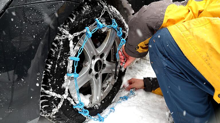 Ein Mann bringt im Salzburger Land Schneeketten an seinem Auto an. Sie sind Pflicht auf zahlreichen Strecken in den Alpen. Ein Mann bringt im Salzburger Land Schneeketten an seinem Auto an. Sie sind Pflicht auf zahlreichen Strecken in den Alpen.