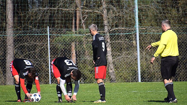 Rhöner Fußball-Nachlese       -  Vertrauen ist gut, Kontrolle ist besser:  Schiedsrichter Wolfgang Hartmann und Deniz Ipek von der SG Bad Brückenau/Römershag schauen ganz genau, dass der Ball ruht und die Schuhe richtig geschnürt sind.