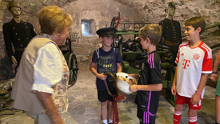 Die Kinder dürfen historische Feuerwehrhelme und -mützen in der Kirchburg Aschfeld aufprobieren. Die Kinder dürfen historische Feuerwehrhelme und -mützen in der Kirchburg Aschfeld aufprobieren.