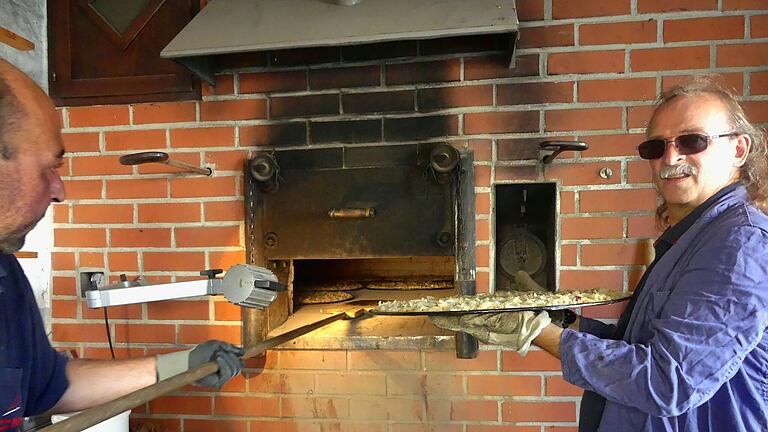 Start für die Zwiebelkuchen: Bis zu elf Bleche mit der köstlichen Spezialitäten können im Hainer Dorfbackofen gleichzeitig gebacken werden. Beim 'Einschließen' der vorbereiteten Bleche Nicola Karch (links) und Ansgar Bick.