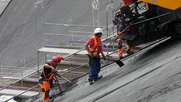 163 Grad heiß: Mit fast 13 000 Tonnen Asphalt wird das Unterbecken ausgekleidet. Die Maschinen hängen an Stahlseilen. 163 Grad heiß: Mit fast 13 000 Tonnen Asphalt wird das Unterbecken ausgekleidet. Die Maschinen hängen an Stahlseilen.
