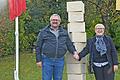 Hand in Hand stehen Kleinrinderfelds Bürgermeister Harald Engbrecht und die Partnerschaftsbeauftragte der Gemeinde Colleville Montgomery, Odile Hardy, vor der frisch enthüllten Stele, die einen weiteren Meilenstein der Städtepartnerschaft zwischen Kleinrinderfeld und Colleville Montgomery kennzeichnet.