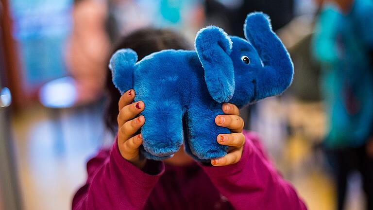 Kinderhaus Blauer Elefant       -  Ein Mädchen hält sich das Maskottchen des Kinderhauses Blauer Elefant vor das Gesicht.