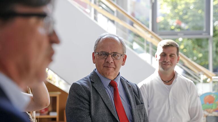 Unterfrankens Regierungspräsident Eugen Ehmann (Mitte) und Günter Höhn, Vorstandsvorsitzender der Winzergenossenschaft Divino (rechts), hören in der Vinothek von Divino deren Geschäftsführer Wendelin Grass zu.