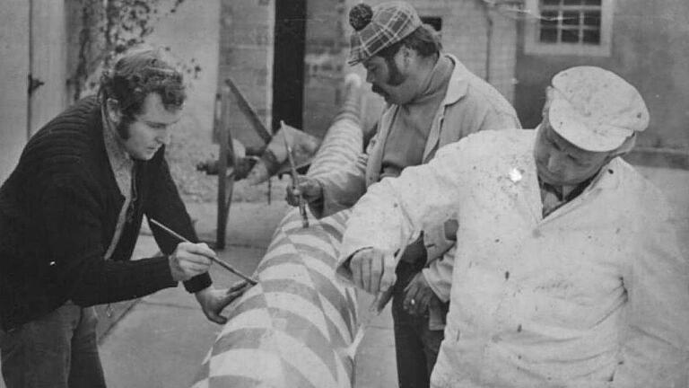 Seit 1976 stellen die Sulzfelder Musikanten den Maibaum am Dorfplatz auf. Viel Geschick gehörten beim ersten Maibaum dazu, um die farblichen Streifen korrekt anzubringen. Das Bild zeigt Gerwin Solf, Josef Guck und Heinrich Herbert. Der Maibaum wurde im Hof von Fridolin Lürzel gestaltet.