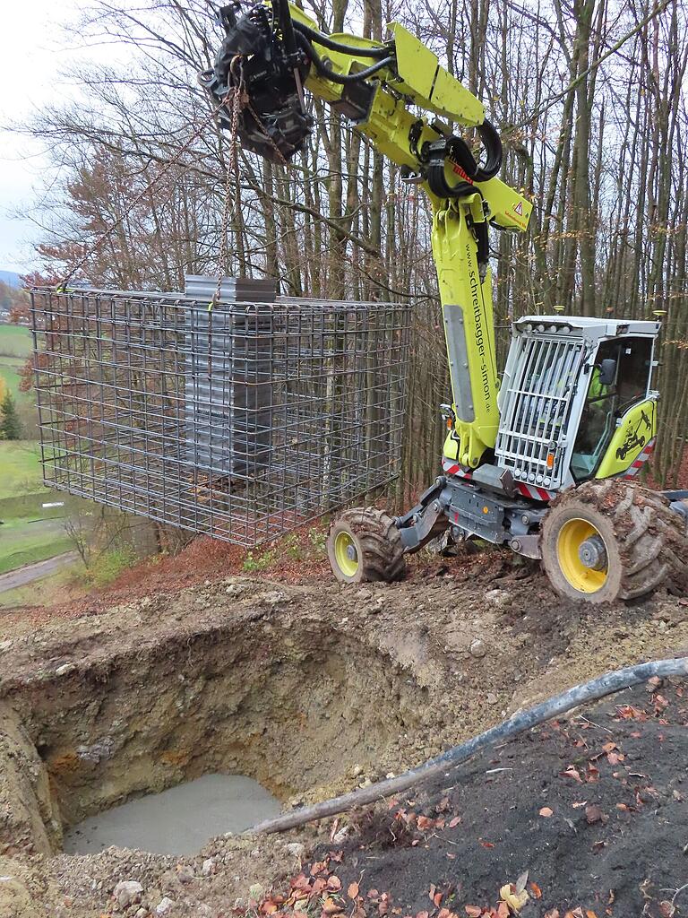 Der Bewehrungskorb am Tragarm wird in die Fundamentgrube eingelassen.