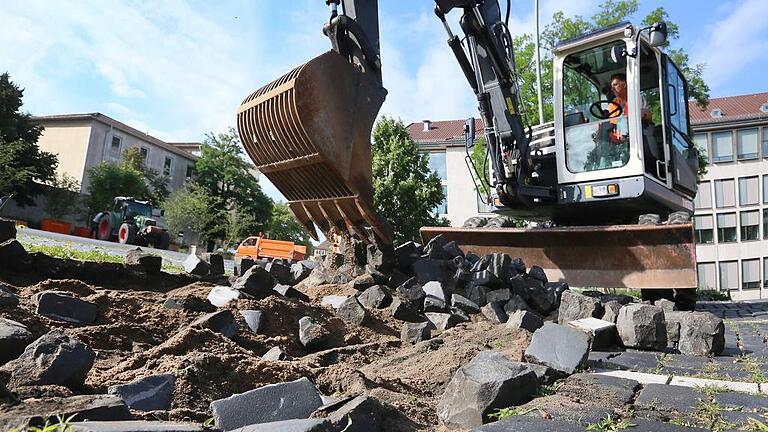 Am Kardinal-Faulhaber-Platz durchkämmt der Bagger das Pflaster: Bis zum Ende der Sommerferien soll der grüne Platz fertig sein. Foto: Theresa Müller