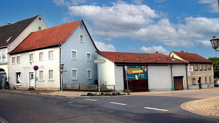 Das Schild „Hier entsteht euer Tante Enso“ hängt schon an einem Gebäude an der Ecke Haupt- und Ludwigstraße in Poppenlauer. Es wird ebenso wie das Haus rechts davon abgerissen.       -  Das Schild „Hier entsteht euer Tante Enso“ hängt schon an einem Gebäude an der Ecke Haupt- und Ludwigstraße in Poppenlauer. Es wird ebenso wie das Haus rechts davon abgerissen.