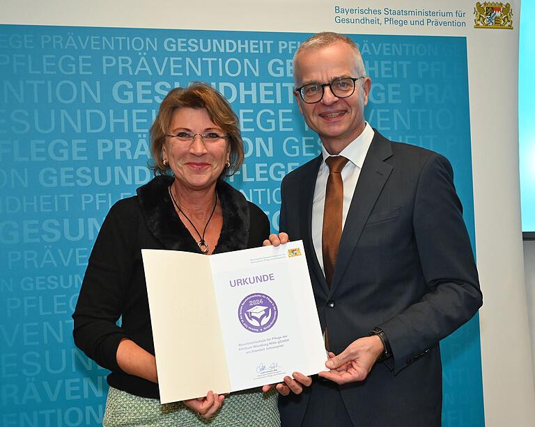 In München nahm Schulleiterin Cordula Kornberger die Urkunde zur Auszeichnung der Berufsfachschule für Pflege des KWM von Dr. Rainer Hutka, Amtschef des Bayerischen Staatsministeriums für Gesundheit, Pflege und Prävention, entgegen. In München nahm Schulleiterin Cordula Kornberger die Urkunde zur Auszeichnung der Berufsfachschule für Pflege des KWM von Dr. Rainer Hutka, Amtschef des Bayerischen Staatsministeriums für Gesundheit, Pflege und Prävention, entgegen.