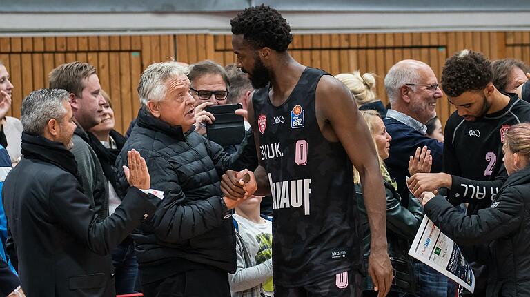 Unternehmensgründer Bernd Freier gratuliert Basketballspieler Gabe Olaseni nach einem Spiel 2018. Freier, der sich selten in der Öffentlichkeit zeigt, hat&nbsp;s.Oliver nach  50 Jahren in fremde Hände gegeben.