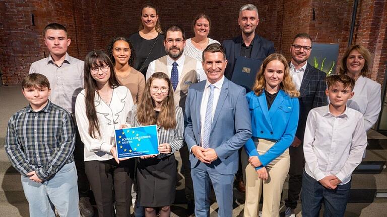 Bei der Preisverleihung: (vordere Reihe von links) Nico Reusch, Leonie Tallafuß, Lea-Marie Schneider, Europaminister Eric Beißwenger, Ronja Mantel, Oliver Zoll; mittlere Reihe von links: Leonard Lutz, Emily Barnes, Bernhard Ruckdäschel, Christian Freiburg, Landtagsabgeordnete Martina Gießhübel; hintere Reihe von links: Dagmar Lux, Kerstin Panzer und Felix Tallafuß.