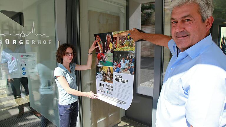 Eine Ausstellung im Bürgerhof findet als Beitrag zu den bundesweiten Fairen Wochen statt. Manuela Teubel und Bürgermeister Thomas Benkert brachten hierzu an den Scheiben Plakate an. Eine Ausstellung im Bürgerhof findet als Beitrag zu den bundesweiten Fairen Wochen statt. Manuela Teubel und Bürgermeister Thomas Benkert brachten hierzu an den Scheiben Plakate an.