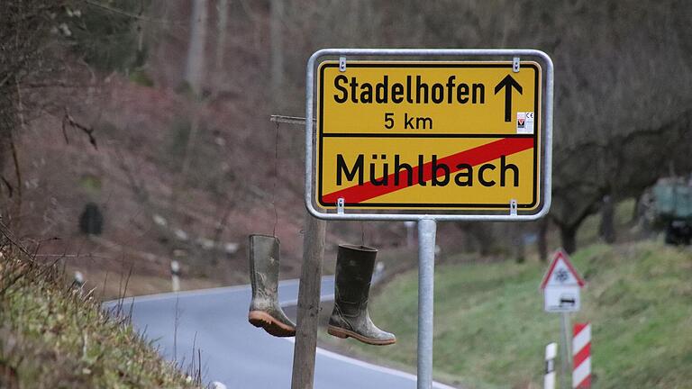 An einem Holzpflock neben dem Ortsschild hängt in Mühlbach ein Paar Gummistiefel. Sie sind ein Symbol für den Protest gegen die geplanten Subventionskürzungen.&nbsp;
