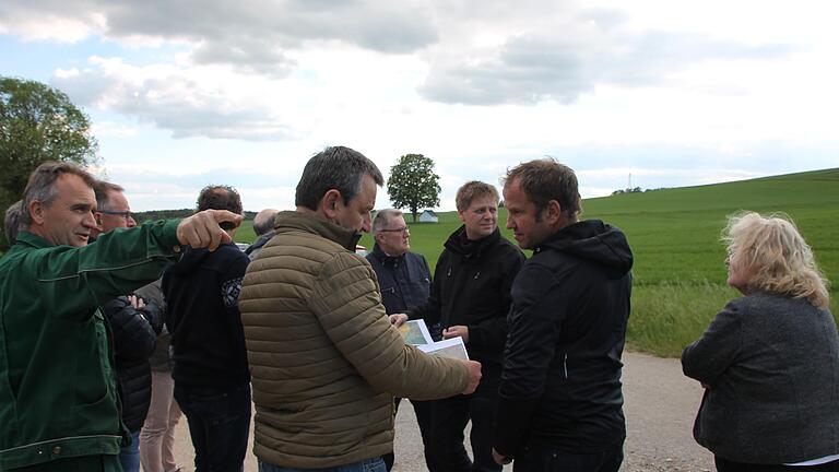 Landwirt Franz-Josef Väth zeigt bei einer Begehung im Mai Bürgermeister Georg Neubauer und Gemeinderäten aus Erlenbach und Tiefenthal vor Ort, wo die Freiflächenphotovoltaikanlage 'Buch' entstehen soll.