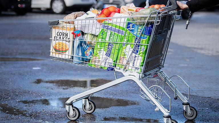 Hamsterkäufe wegen Corona? Ein Kunde schiebt einen bis zum Rand gefüllten Einkaufswagen über den Parkplatz eines Supermarktes.