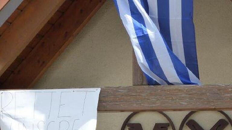Die RV-Filiale Mechenried (großes Bild): Die Filialen Mechenried, Humprechtshausen und Aidhausen sollen geschlossen werden. Sichtbarer Protest dagegen am Aidhäuser Bankgebäude – mit griechischer Flagge und Plakat (kleines Bild). Die RV-Filiale Mechenried (großes Bild): Die Filialen Mechenried, Humprechtshausen und Aidhausen sollen geschlossen werden. Sichtbarer Protest dagegen am Aidhäuser Bankgebäude – mit griechischer Flagge und Plakat (kleines Bild).