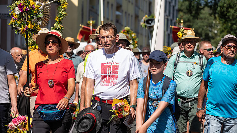 Um die 300 Wallfahrerinnen und Wallfahrer kehren am Samstag (24.08.24) bei sengender Hitze von ihrer Pilger-Wallfahrt vom Kreuzberg in der Rhön nach Würzburg zurück. Auf dem Weg zum Gottesdienst im Dom werden die Wallfahrer von zahlreichen Menschen mit Blumen empfangen.