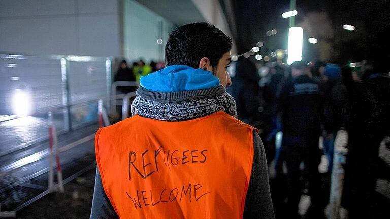 Flüchtlinge am LaGeSo       -  Willkommensgruß: Ein Helfer stand vor dem Landesamt für Gesundheit und Soziales (Lageso) in Berlin. In dem Amt können Flüchtlinge sich registrieren lassen oder erste Unterstützungsleistungen erhalten.